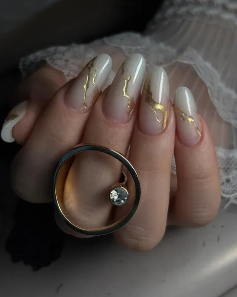 Uñas almendradas en tono lechoso con detalles dorados